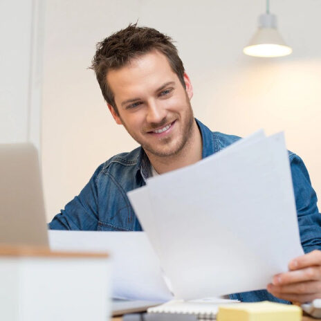 Man smiling while reviewing documents at desk.